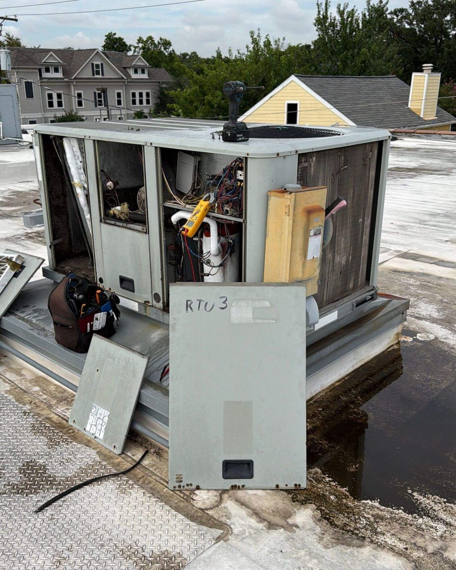 Rooftop unit with its service panels off on a flat roof