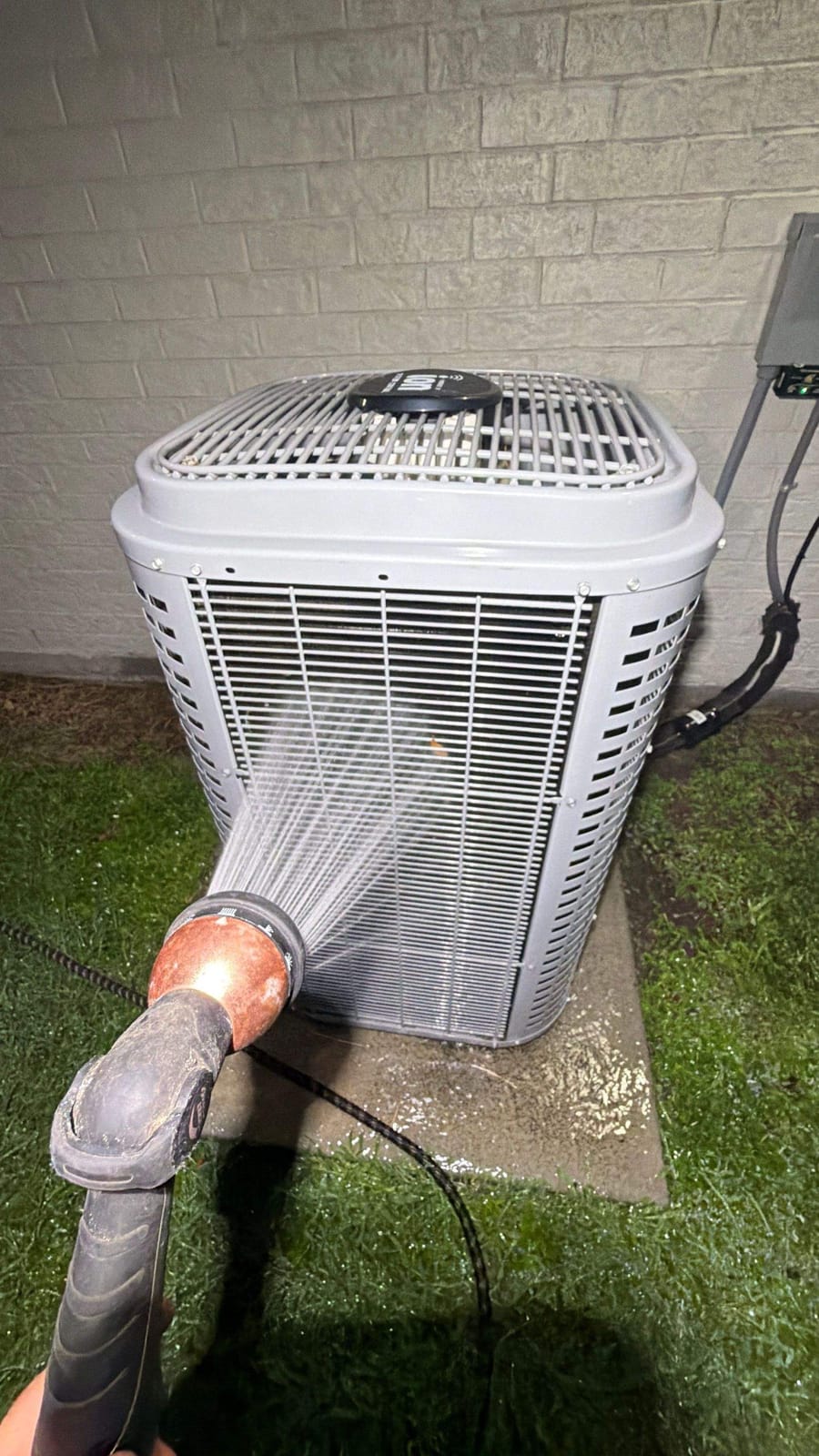 ColdSolutions technician rinsing down a condenser coil during AC maintenance