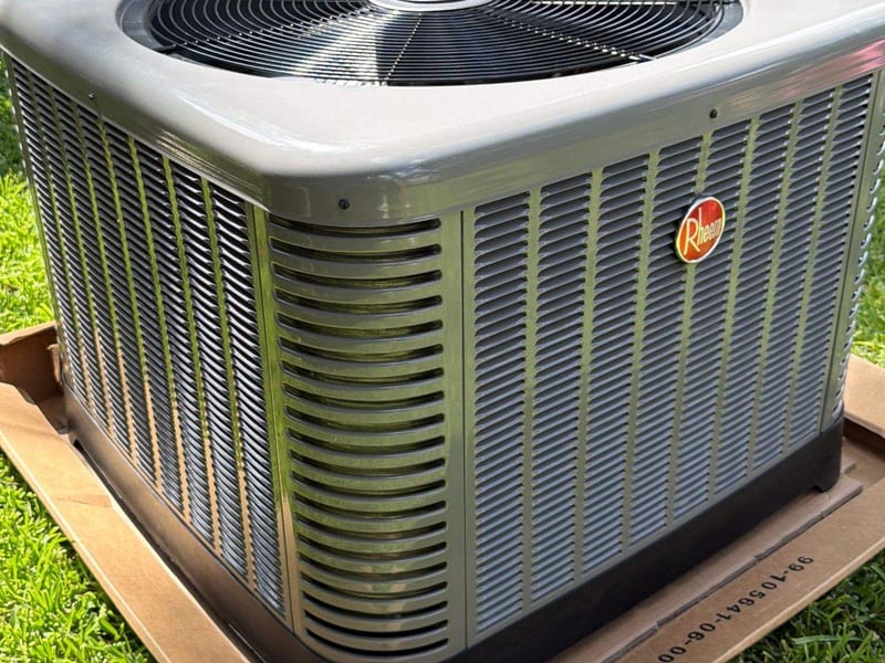 New Rheem condenser set on its pad in the grass