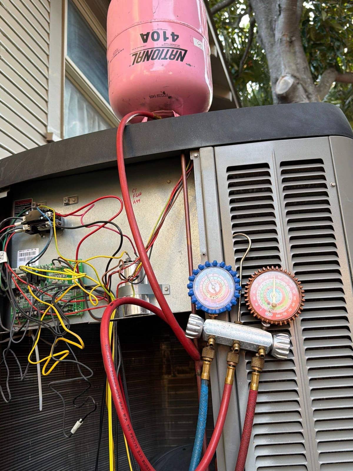Refrigerant gauges and a cylinder at an outdoor unit during a repair