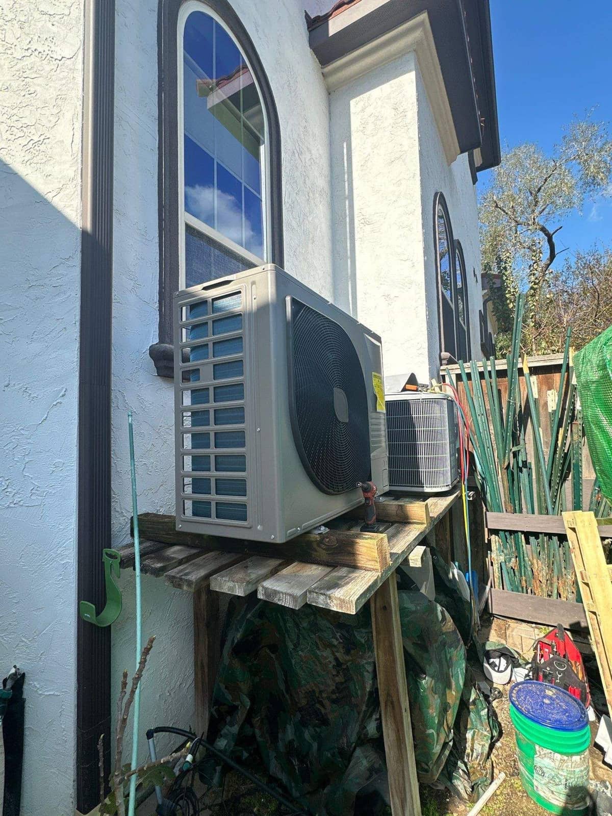 Ductless outdoor unit on a wall stand under a blue sky