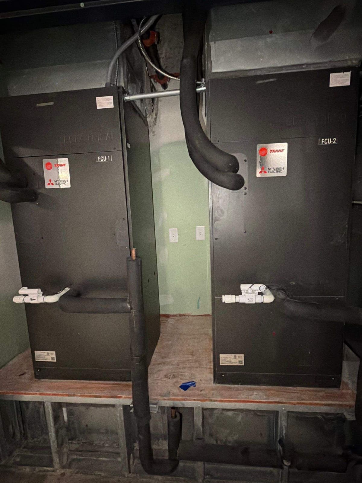 Commercial air handlers on a stand in a dark mechanical room