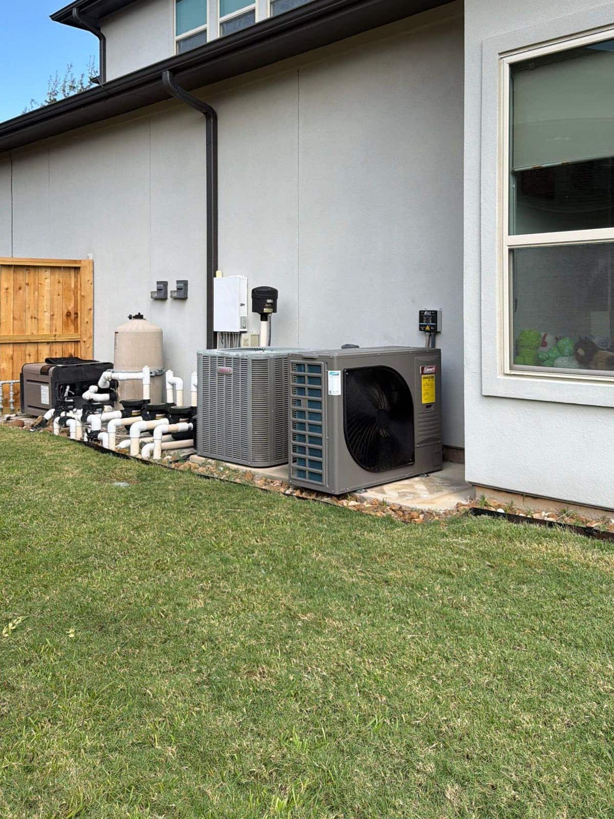 Outdoor units beside a modern two-story home and its lawn