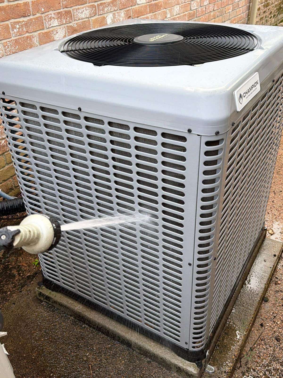 Technician rinsing a condenser coil with a hose