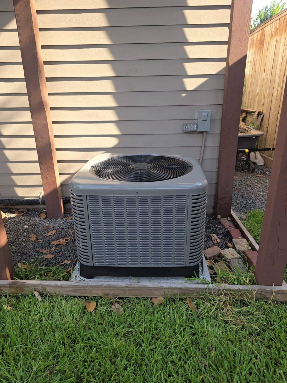 Rheem condenser on a pad in a fenced backyard