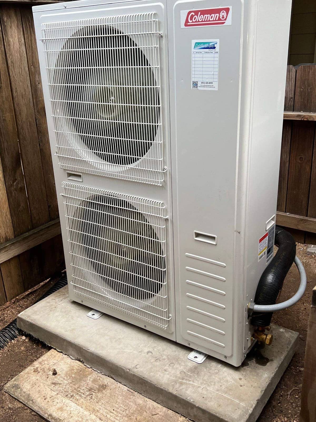 Coleman outdoor unit on a pad beside a wood fence