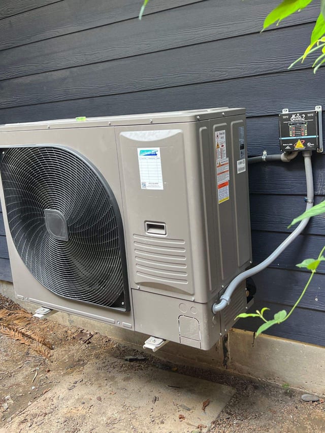 Ductless outdoor unit mounted on dark blue siding